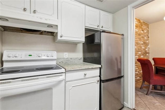 kitchen featuring brick wall, stainless steel refrigerator, white cabinets, white electric range oven, and light tile patterned floors