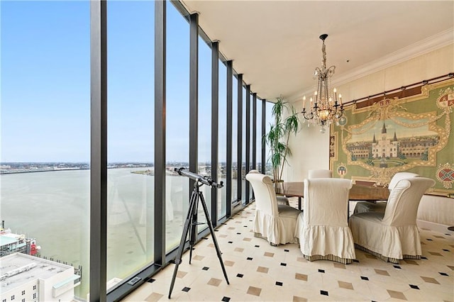 dining area featuring expansive windows, ornamental molding, a water view, and an inviting chandelier