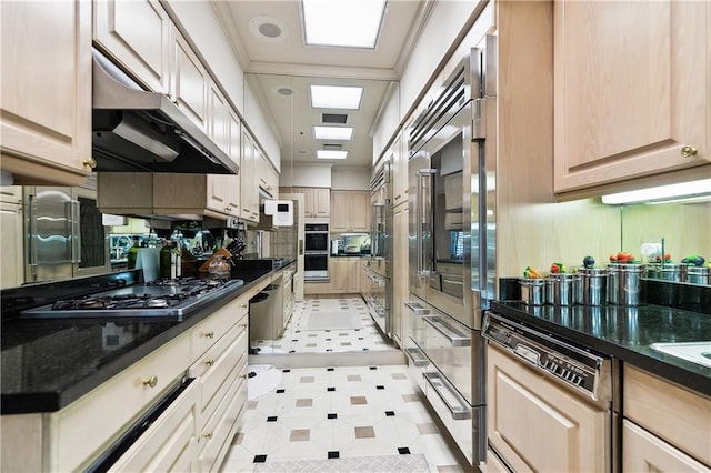 kitchen featuring light brown cabinetry, ornamental molding, stainless steel appliances, and dark stone counters