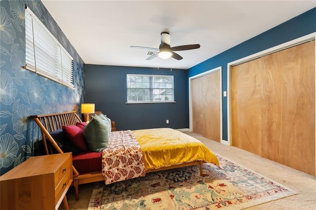 carpeted bedroom featuring two closets and ceiling fan