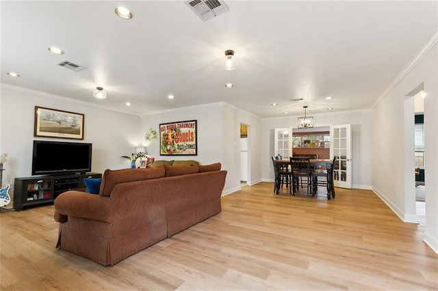 living room with ornamental molding, a chandelier, and light hardwood / wood-style flooring