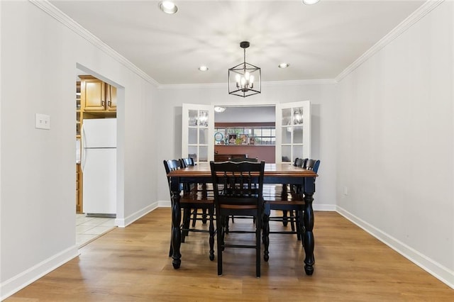 dining room with crown molding, a notable chandelier, and light hardwood / wood-style flooring