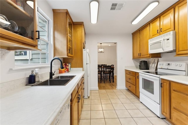 kitchen with sink, white appliances, hanging light fixtures, and light tile patterned floors