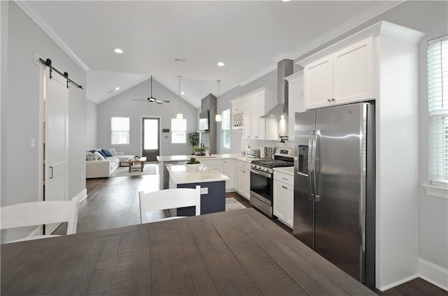 kitchen with white cabinetry, a center island, stainless steel appliances, a barn door, and wall chimney range hood