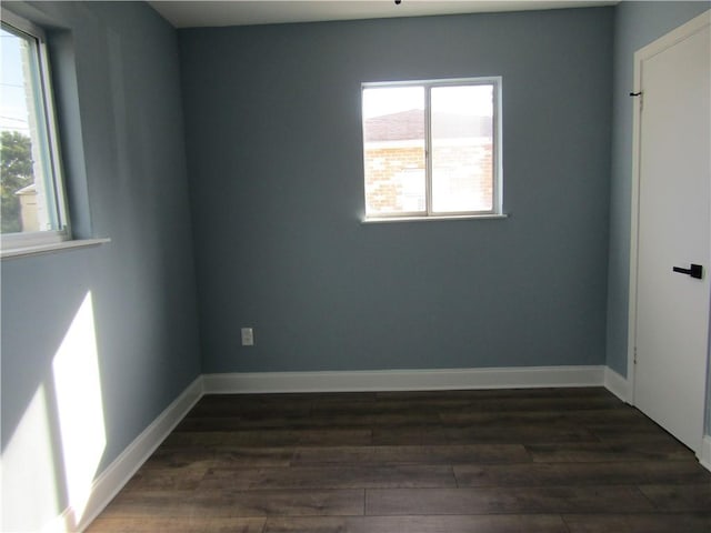 empty room with dark wood-type flooring and a wealth of natural light