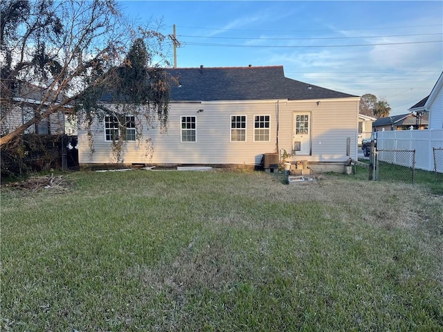 back of property with central AC and a lawn