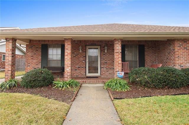 view of exterior entry with a yard and covered porch