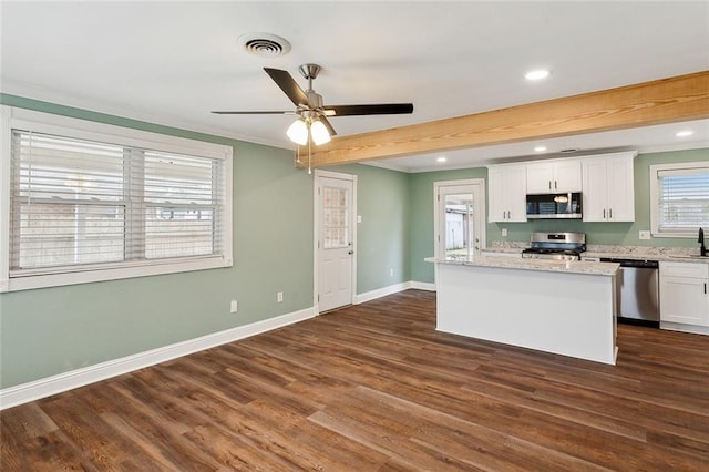 kitchen featuring white cabinetry, light stone counters, a kitchen island, stainless steel appliances, and beam ceiling