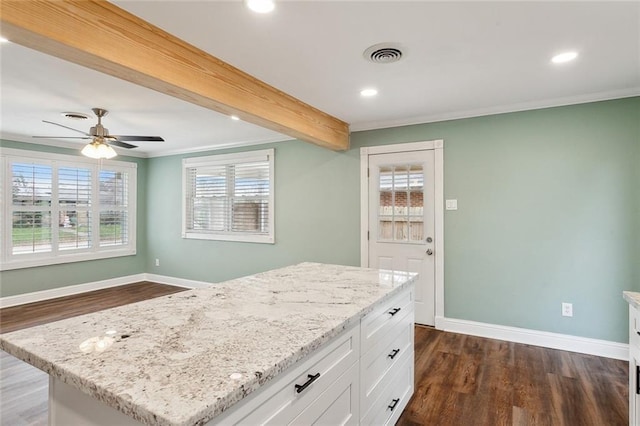 kitchen with beamed ceiling, white cabinetry, a center island, light stone counters, and dark wood-type flooring