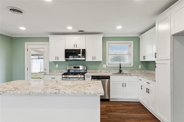 kitchen featuring sink, light stone counters, crown molding, appliances with stainless steel finishes, and white cabinets