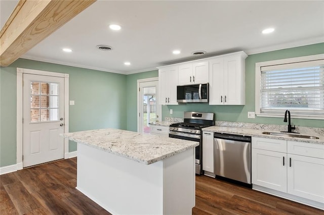 kitchen with a kitchen island, appliances with stainless steel finishes, dark hardwood / wood-style floors, white cabinets, and light stone countertops