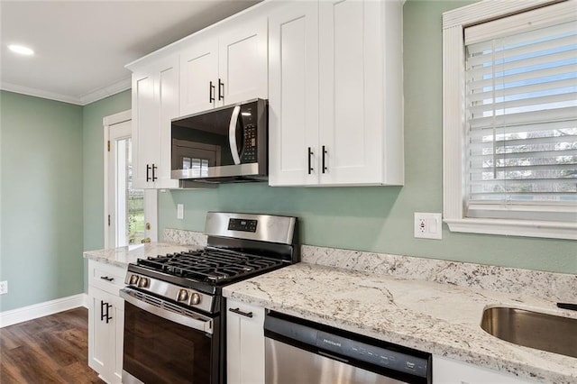 kitchen with white cabinetry, appliances with stainless steel finishes, ornamental molding, and plenty of natural light