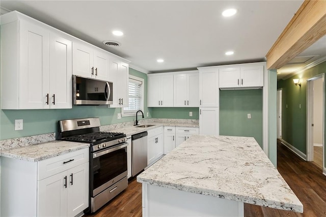 kitchen with appliances with stainless steel finishes, a center island, sink, and white cabinets