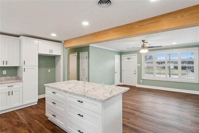 kitchen featuring beam ceiling, a kitchen island, white cabinets, and light stone counters