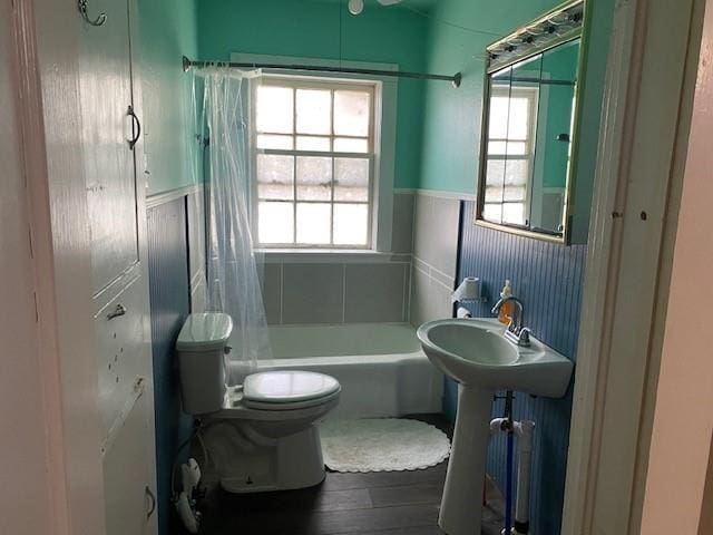 bathroom with shower / tub combo with curtain, toilet, and a healthy amount of sunlight