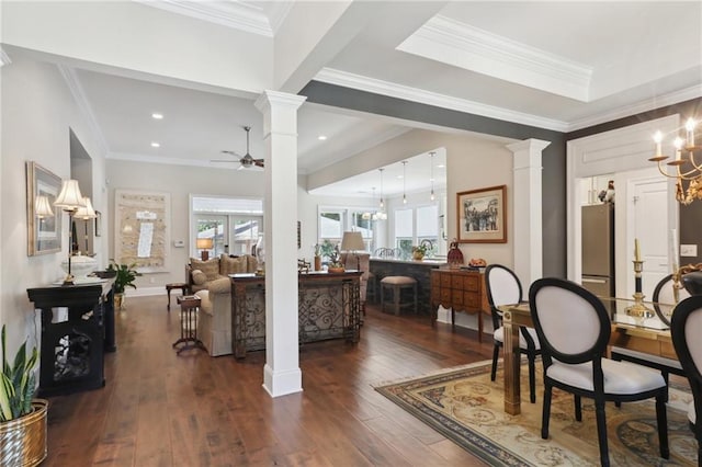 interior space featuring dark hardwood / wood-style flooring, a wealth of natural light, ceiling fan with notable chandelier, and ornate columns