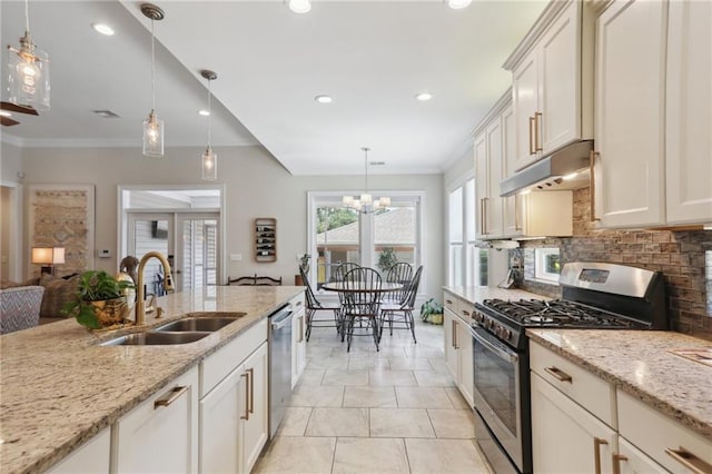 kitchen with decorative light fixtures, sink, backsplash, stainless steel appliances, and light stone countertops