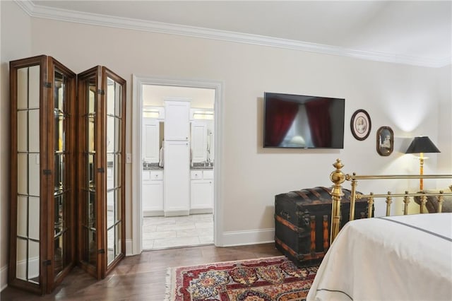 bedroom with dark hardwood / wood-style floors, ornamental molding, and connected bathroom