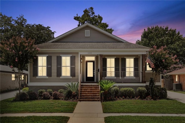 view of front of home with a porch, a yard, and central air condition unit