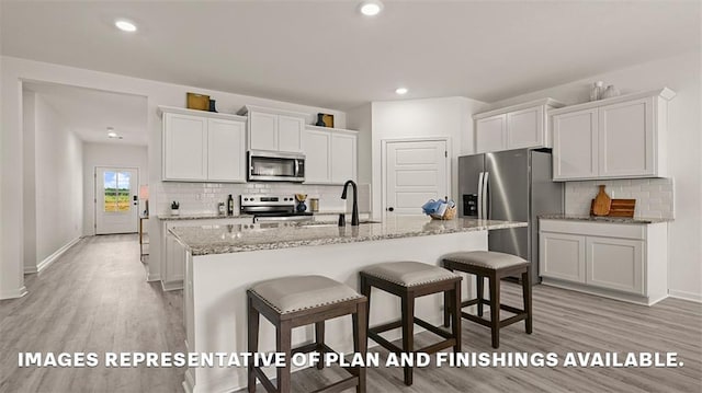kitchen with stainless steel appliances, backsplash, light wood finished floors, and a sink