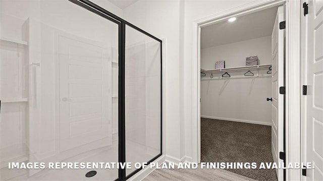 bathroom featuring a stall shower, baseboards, and a spacious closet