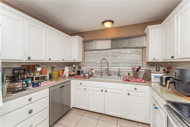 kitchen featuring sink, light tile patterned floors, white cabinetry, backsplash, and stainless steel appliances