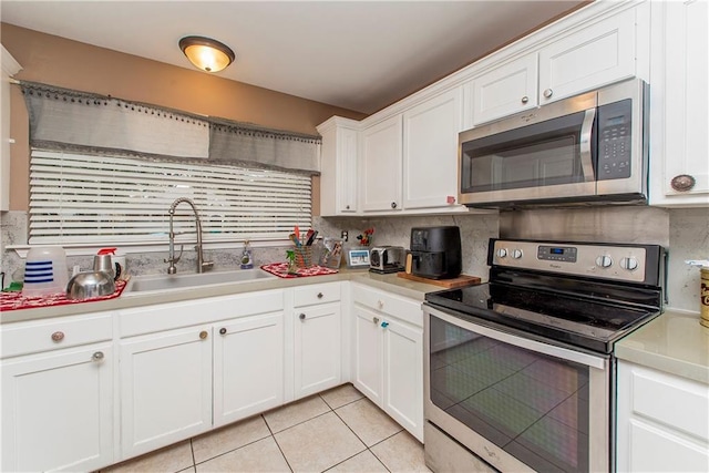 kitchen with stainless steel appliances, white cabinetry, sink, and decorative backsplash