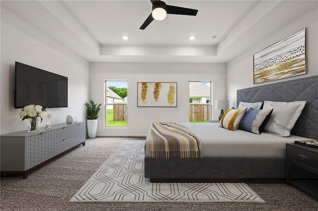 carpeted bedroom with multiple windows, ceiling fan, and a tray ceiling