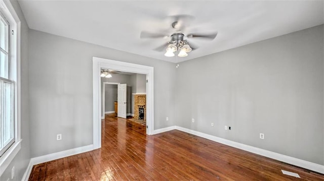 unfurnished room with wood-type flooring, a ceiling fan, baseboards, and a wealth of natural light
