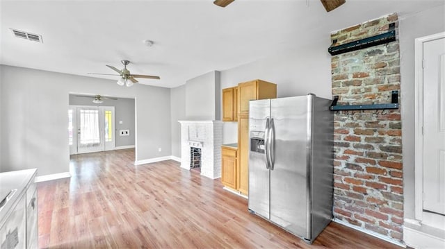 kitchen featuring a brick fireplace, a ceiling fan, visible vents, and stainless steel fridge with ice dispenser