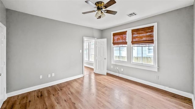 unfurnished room with visible vents, baseboards, ceiling fan, and wood finished floors