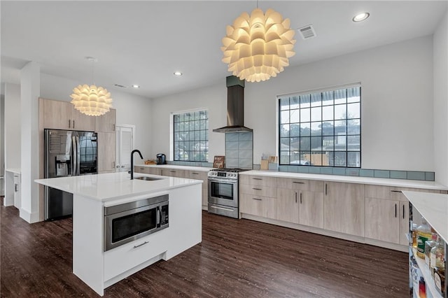 kitchen with stainless steel appliances, sink, hanging light fixtures, and wall chimney range hood