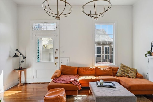 living area featuring a wealth of natural light, ornamental molding, wood finished floors, and a notable chandelier