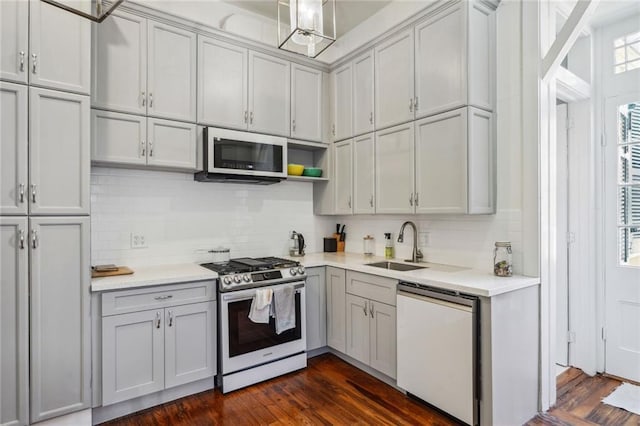 kitchen featuring stainless steel gas range, a sink, dishwasher, light countertops, and backsplash
