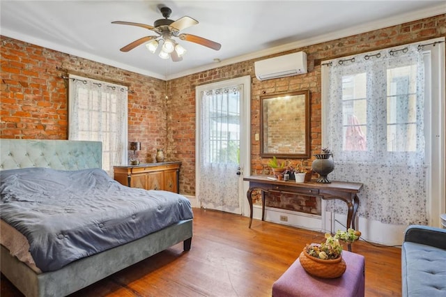 bedroom featuring an AC wall unit, brick wall, and wood finished floors