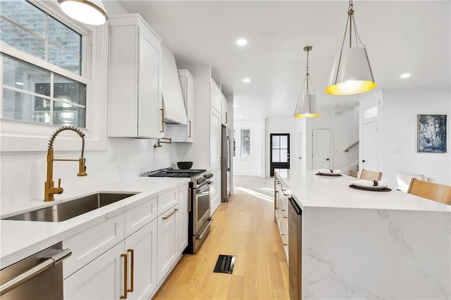 kitchen with stainless steel appliances, white cabinetry, hanging light fixtures, and sink