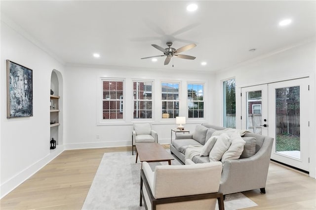 living room with ceiling fan, built in shelves, a healthy amount of sunlight, and light wood-type flooring