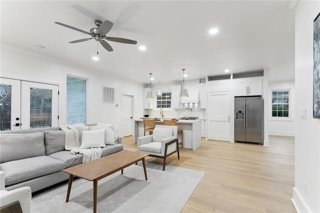 living room with french doors, sink, ceiling fan, and light hardwood / wood-style flooring