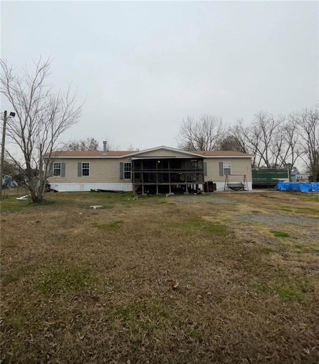 rear view of property featuring a yard and a sunroom