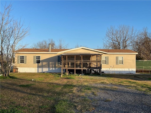 back of property with a sunroom and a lawn