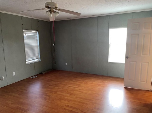 unfurnished room with a ceiling fan, light wood-type flooring, visible vents, and a textured ceiling