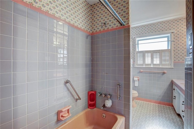 full bathroom with tile walls, vanity, tiled shower / bath, tile patterned floors, and toilet