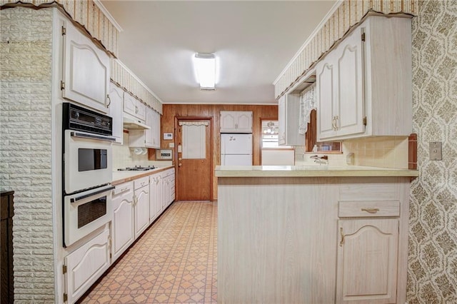 kitchen with backsplash, white appliances, and kitchen peninsula