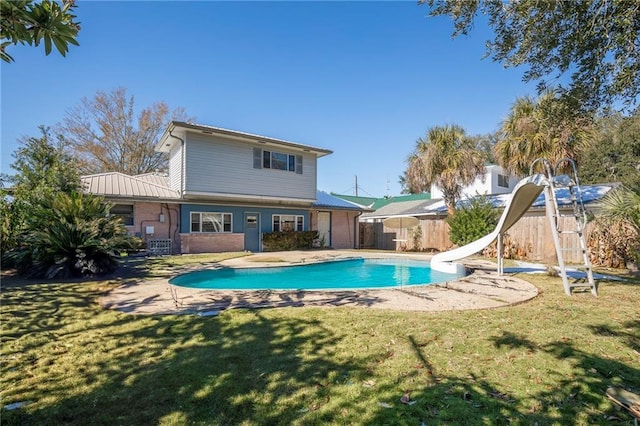 rear view of property with a fenced in pool and a yard