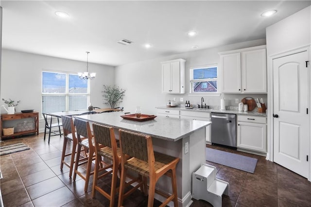 kitchen featuring hanging light fixtures, white cabinetry, stainless steel dishwasher, and a kitchen bar