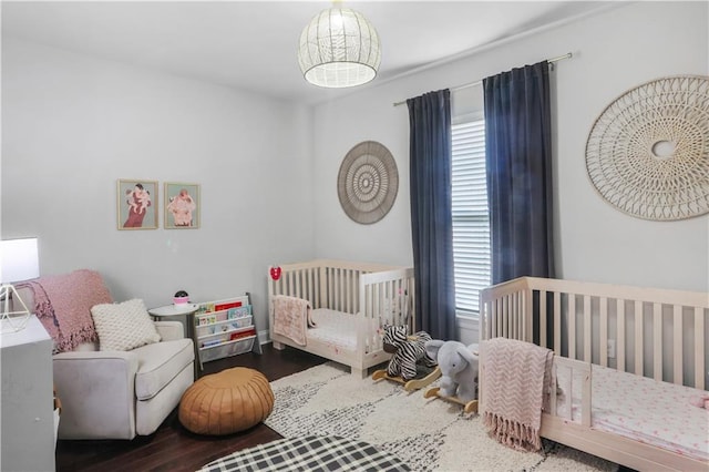 bedroom featuring multiple windows, wood-type flooring, and a nursery area