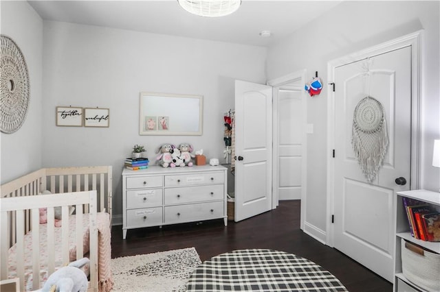 bedroom with a nursery area, dark hardwood / wood-style floors, and vaulted ceiling