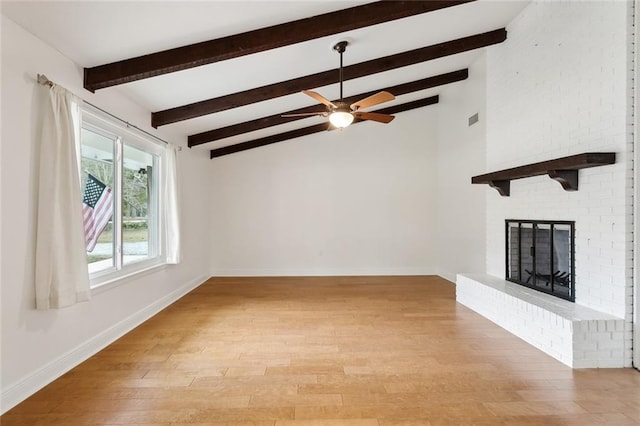 unfurnished living room with a brick fireplace, light hardwood / wood-style flooring, lofted ceiling with beams, and ceiling fan