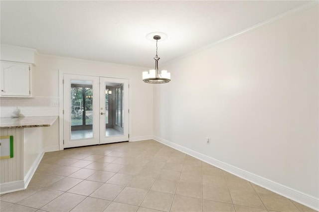 unfurnished dining area with crown molding, a notable chandelier, light tile patterned floors, and french doors