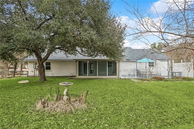 rear view of property featuring a sunroom and a lawn